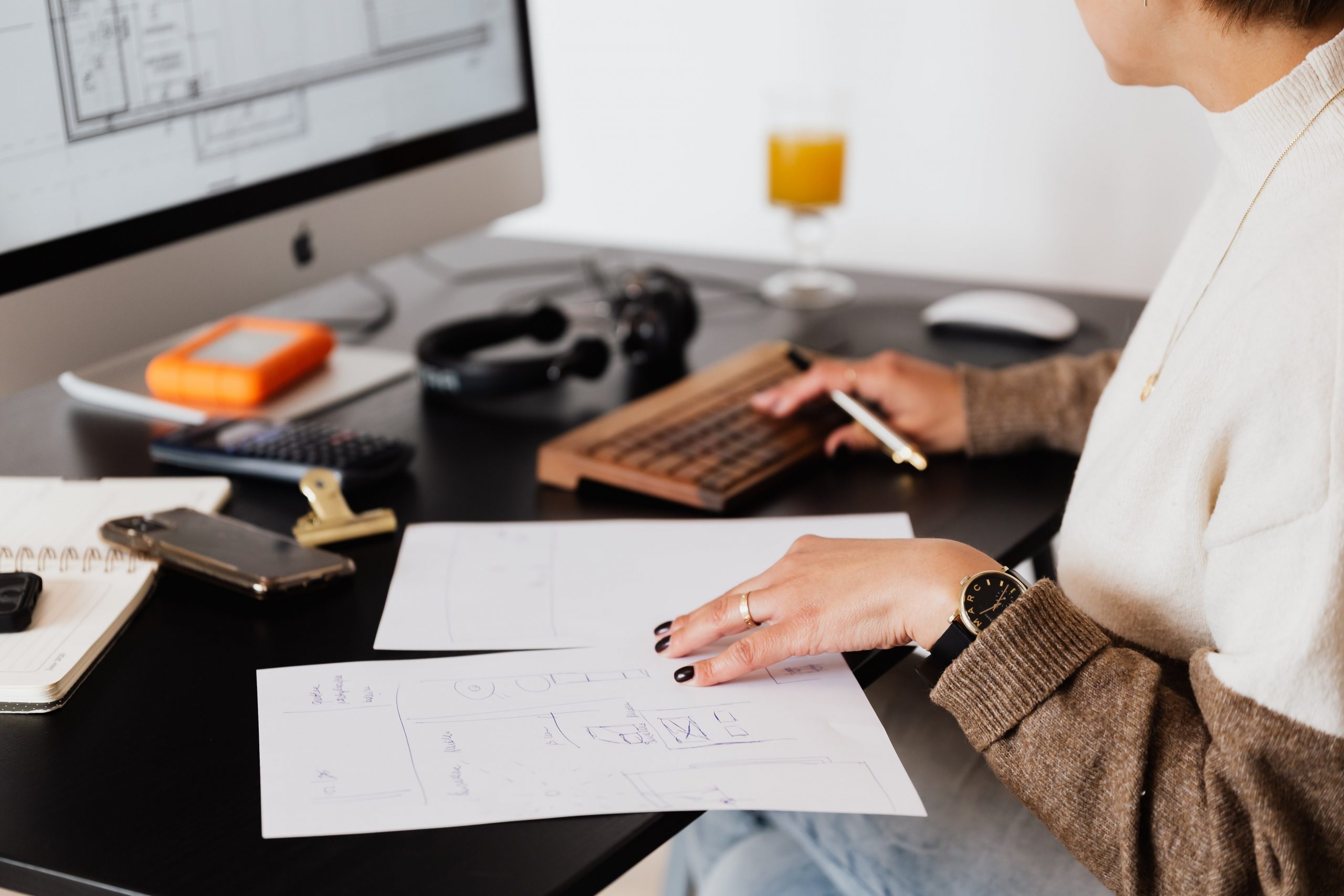 person at a desk with computer, reviewing papers