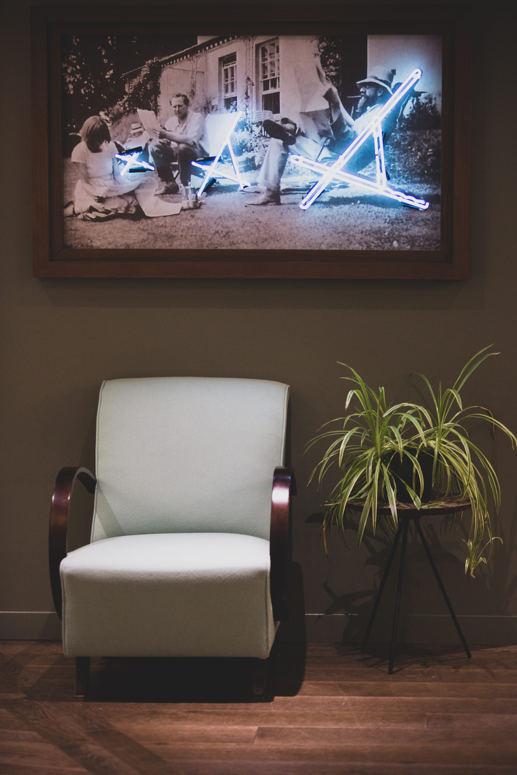 chair with plant on the right and picture frame above